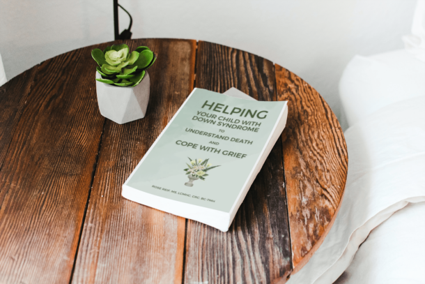 The book Helping Your Child with Down Syndrome to Understand Death and Cope with Grief by Rose Reif on a bedside table